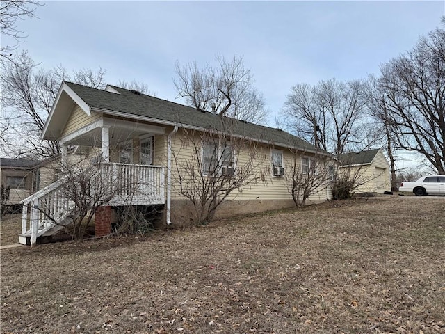 view of home's exterior featuring covered porch, a shingled roof, stairway, and a garage