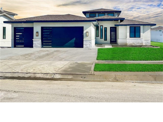 prairie-style home featuring stone siding, concrete driveway, an attached garage, and stucco siding