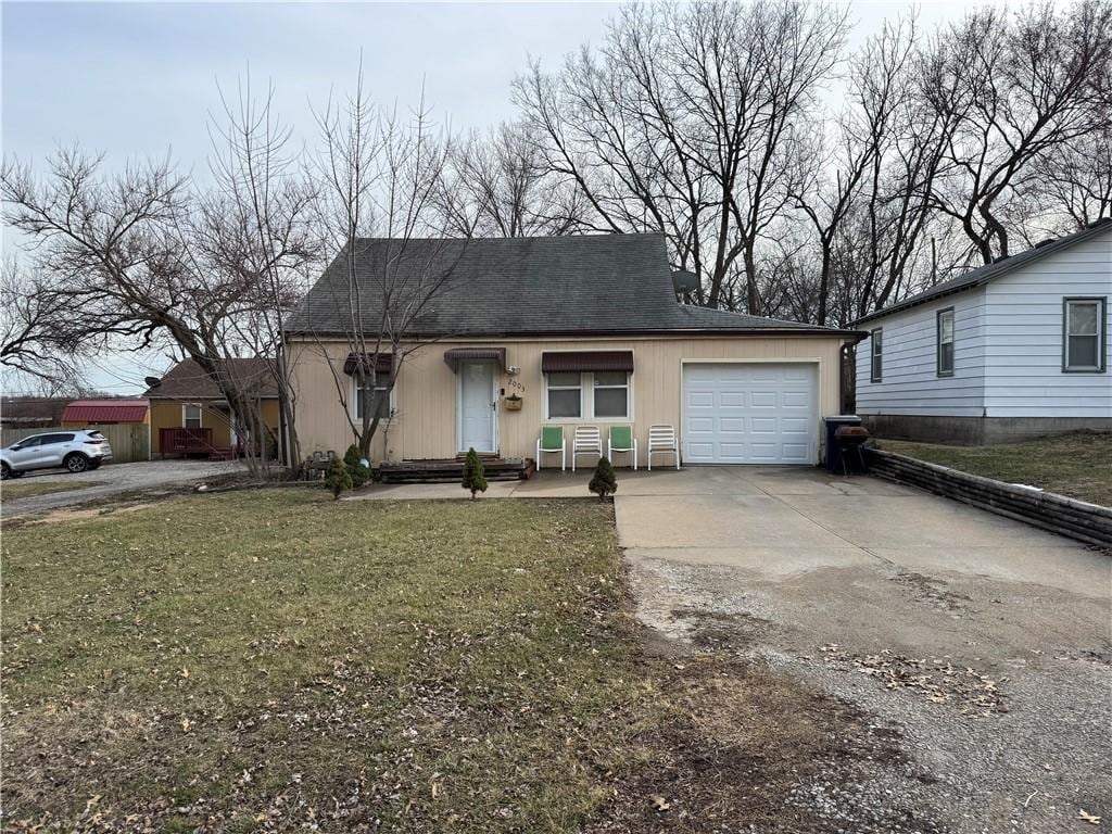 view of front of house with concrete driveway, an attached garage, and a front yard