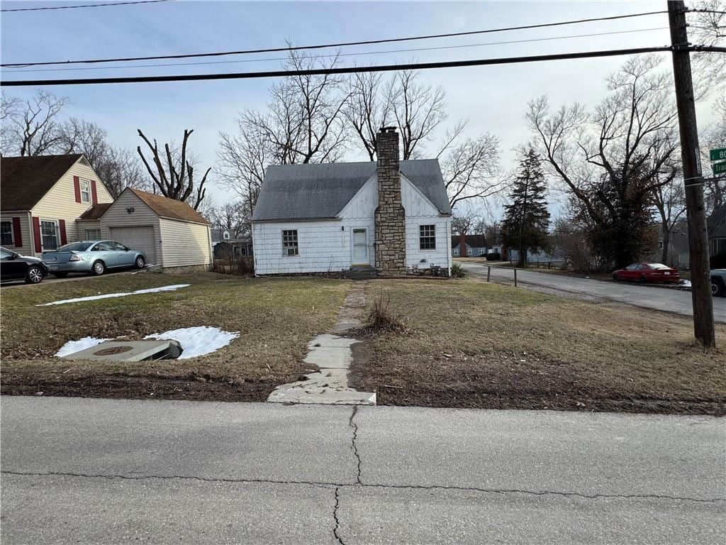 view of front of property with a garage, a front lawn, and a chimney