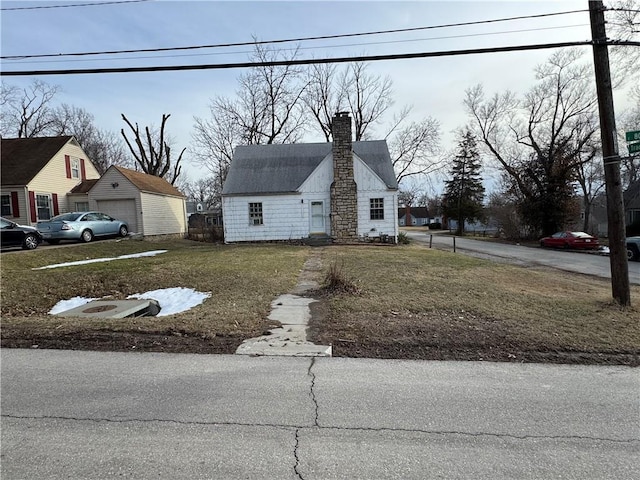 view of front of property with a garage, a front lawn, and a chimney