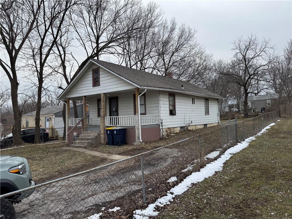 view of front of home with a fenced front yard, a chimney, a porch, and a shingled roof