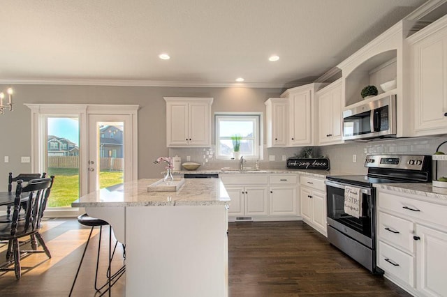 kitchen with white cabinets, decorative backsplash, a kitchen island, appliances with stainless steel finishes, and open shelves