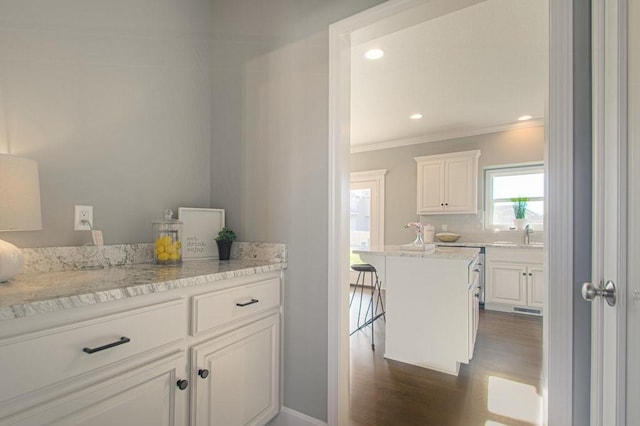 9100 NE 98th Ter, Kansas City, MO 64157 - kitchen with crown molding, white cabinets, dark wood-style floors, a breakfast bar, and light stone countertops