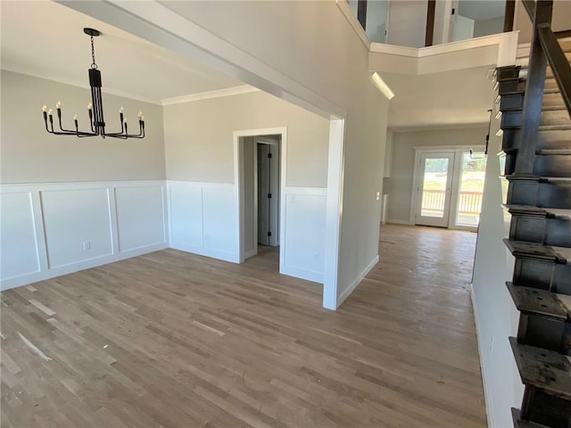 9100 NE 98th Ter, Kansas City, MO 64157 - unfurnished dining area with a chandelier, wood finished floors, stairway, ornamental molding, and wainscoting