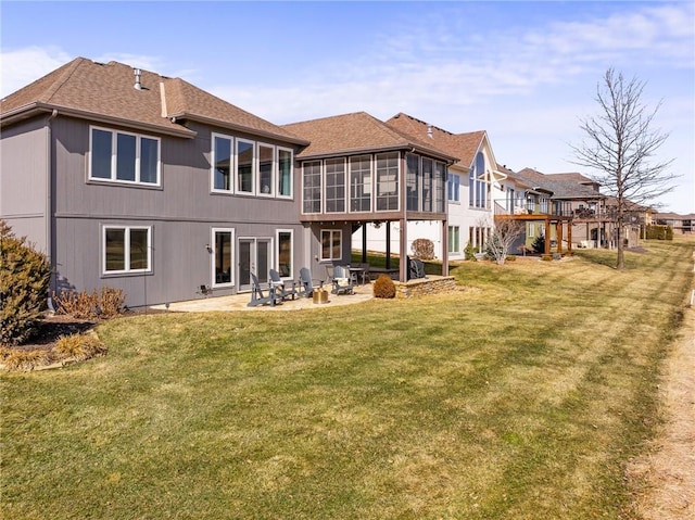 back of property featuring roof with shingles, a lawn, a patio area, and a sunroom