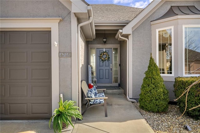 property entrance with a garage, roof with shingles, and stucco siding