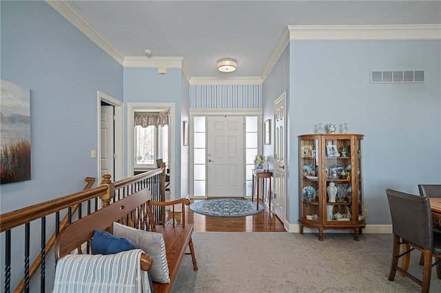 foyer entrance featuring ornamental molding, carpet flooring, visible vents, and baseboards