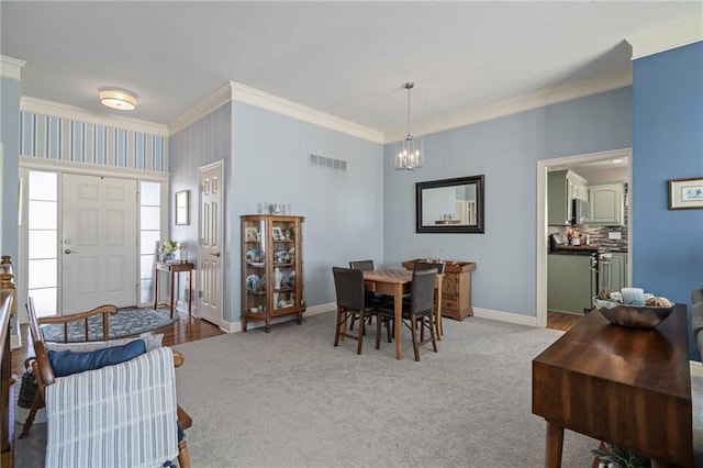 dining area with a chandelier, visible vents, baseboards, carpet, and crown molding