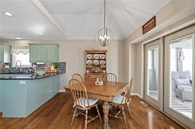 dining space featuring vaulted ceiling, a notable chandelier, dark wood finished floors, and baseboards