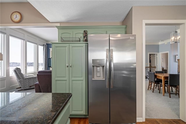 kitchen featuring dark wood-type flooring, stainless steel fridge, dark stone counters, and green cabinetry