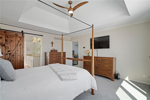 bedroom with carpet floors, a raised ceiling, visible vents, and a barn door