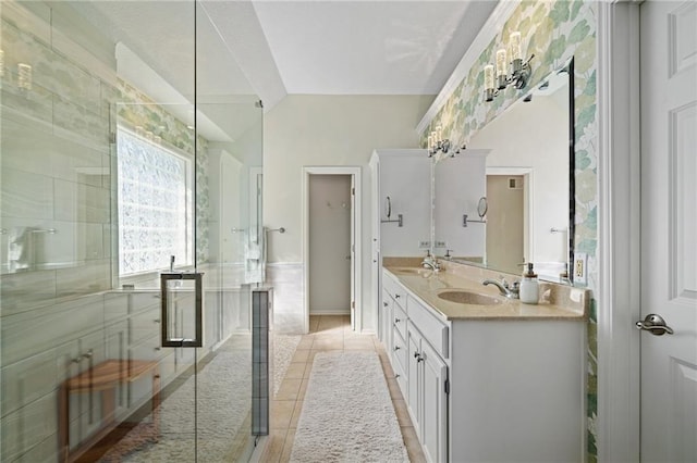 bathroom with double vanity, a stall shower, a sink, and tile patterned floors