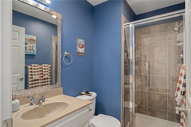 bathroom with toilet, a shower stall, and vanity