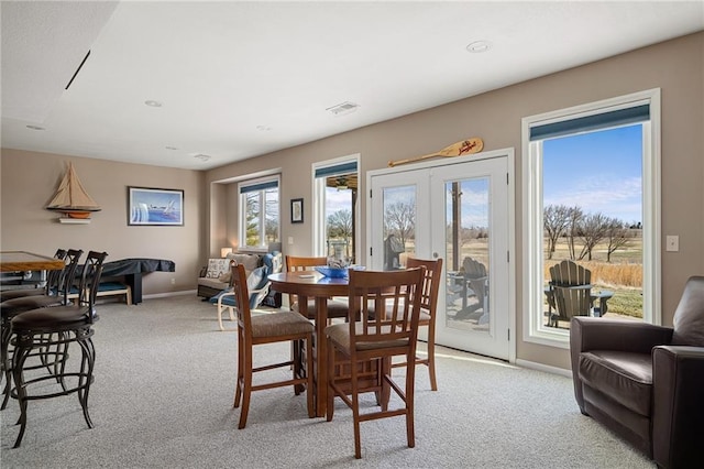 dining space with light carpet, baseboards, visible vents, and french doors