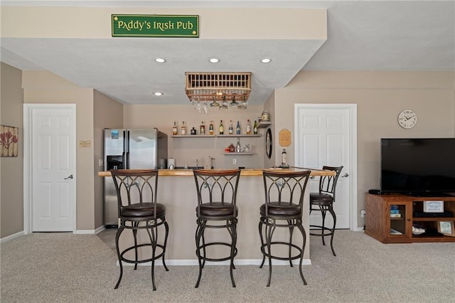 bar with light carpet, wet bar, stainless steel refrigerator with ice dispenser, and recessed lighting