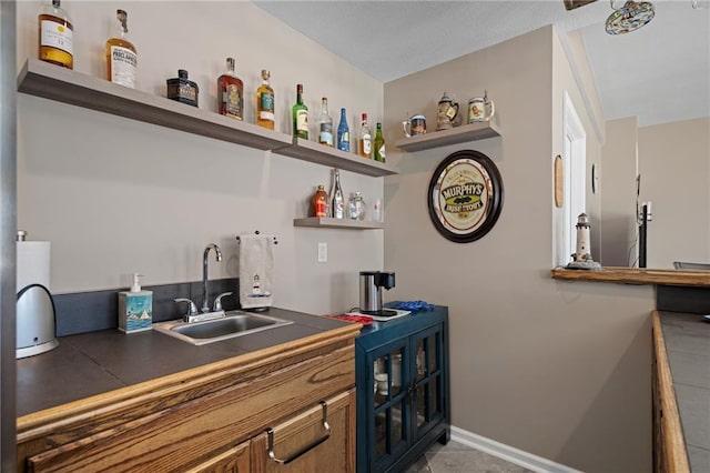 bar with indoor wet bar, a sink, and baseboards