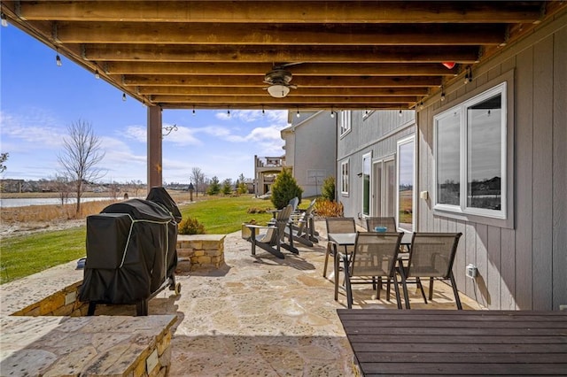 view of patio with a water view, grilling area, and outdoor dining space