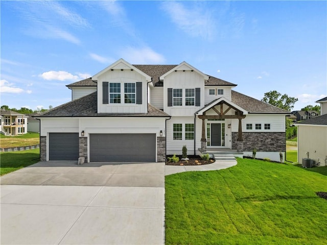 view of front of house featuring a front yard, a shingled roof, concrete driveway, stone siding, and board and batten siding