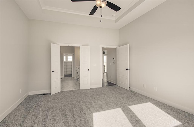 unfurnished bedroom featuring ceiling fan, baseboards, a raised ceiling, and carpet
