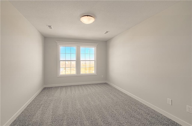 carpeted empty room with visible vents, baseboards, and a textured ceiling