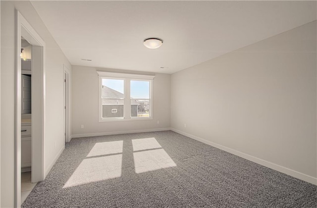 spare room featuring baseboards and light carpet