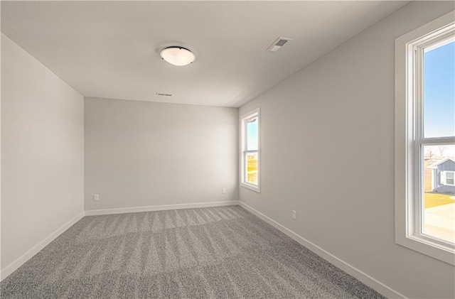 unfurnished room featuring carpet, visible vents, and baseboards