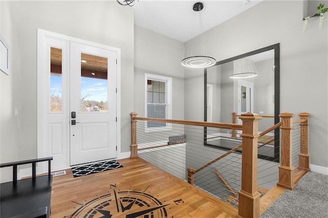 foyer entrance featuring baseboards, wood-type flooring, and visible vents