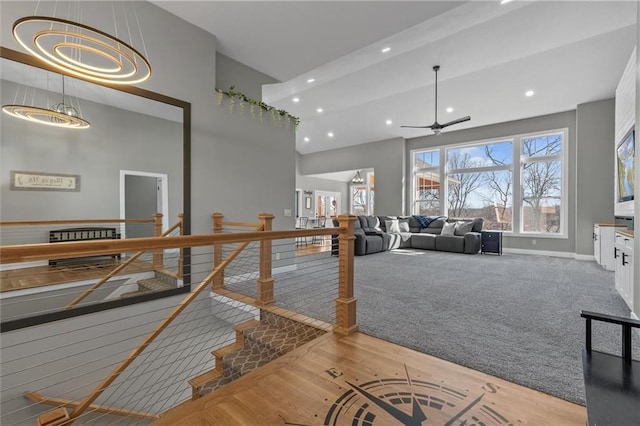 interior space with carpet, baseboards, recessed lighting, ceiling fan, and a towering ceiling