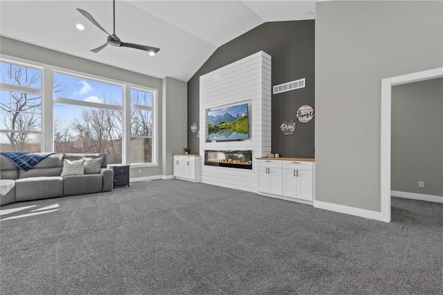 unfurnished living room featuring a glass covered fireplace, baseboards, dark colored carpet, and a ceiling fan