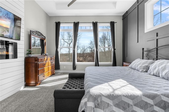 bedroom featuring a fireplace, a raised ceiling, and carpet floors