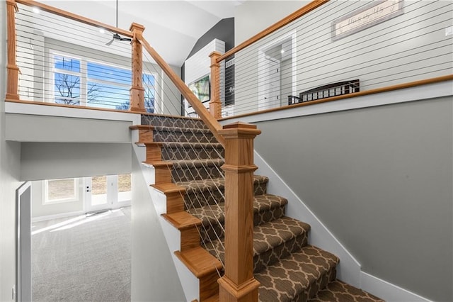 stairs with carpet flooring, baseboards, and high vaulted ceiling