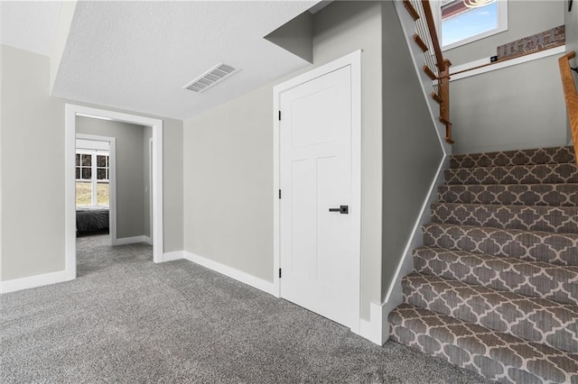 stairway with visible vents, plenty of natural light, carpet, and baseboards