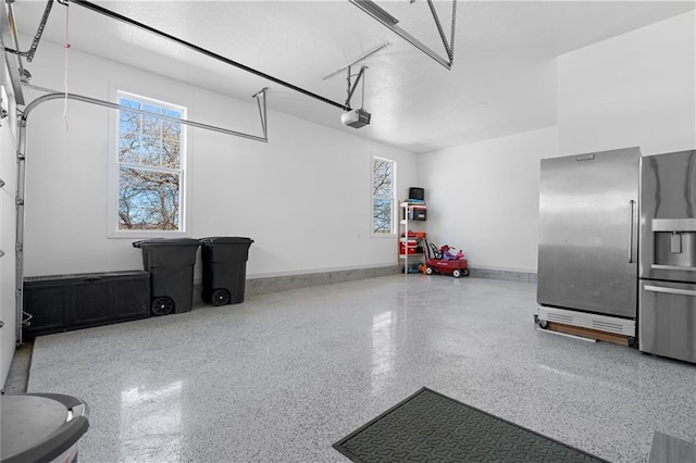 garage featuring stainless steel fridge, a garage door opener, and baseboards