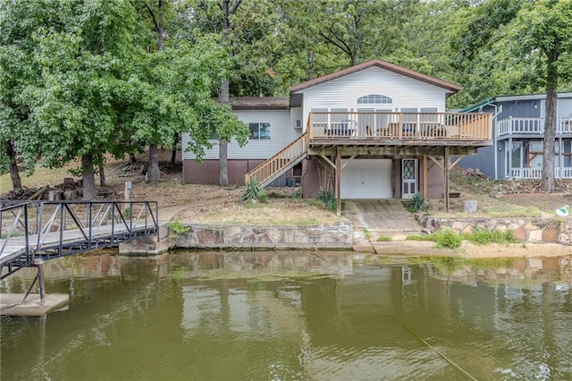 rear view of property featuring stairs, a deck with water view, and an attached garage