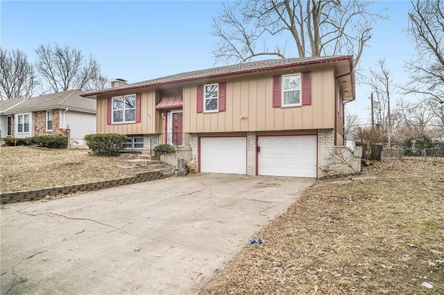 raised ranch with a garage, concrete driveway, brick siding, and a chimney