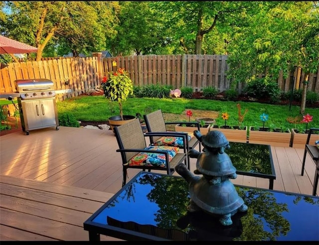 wooden deck featuring a fenced backyard, a grill, and a yard