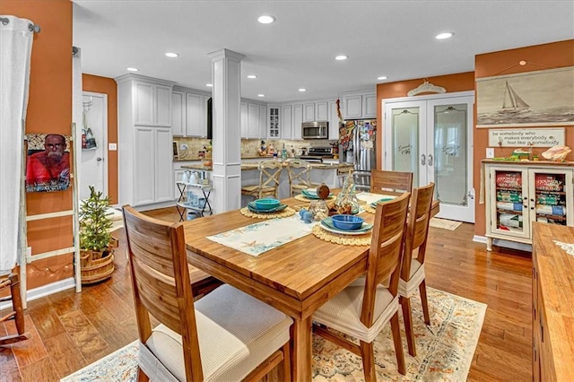 dining area with light wood-style floors, recessed lighting, french doors, and decorative columns