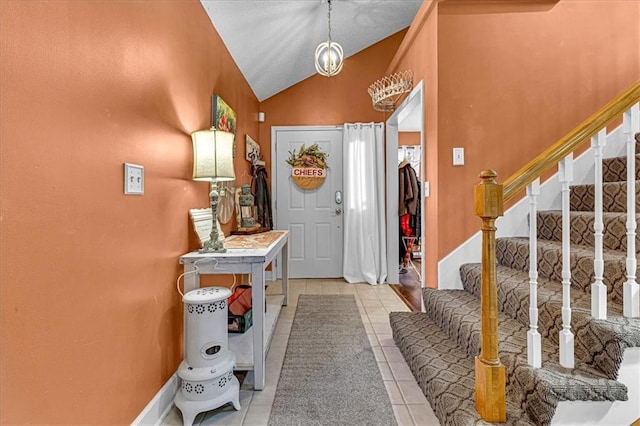 entryway with vaulted ceiling, stairway, and light tile patterned floors