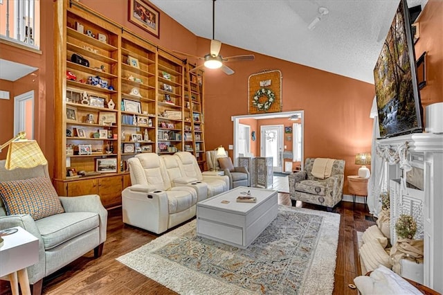 living area with built in features, a ceiling fan, dark wood-style flooring, a textured ceiling, and high vaulted ceiling