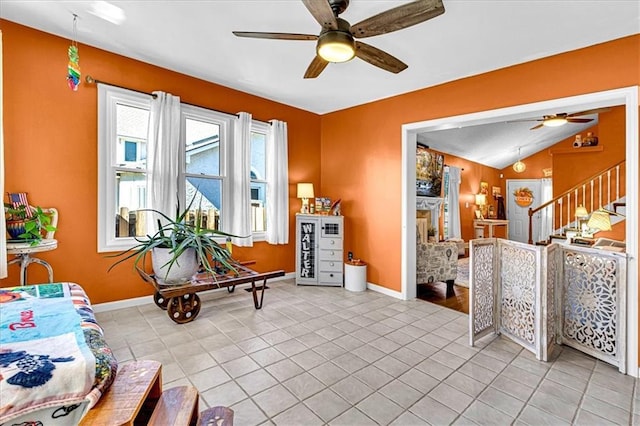 sitting room with a fireplace, light tile patterned floors, a ceiling fan, vaulted ceiling, and stairs