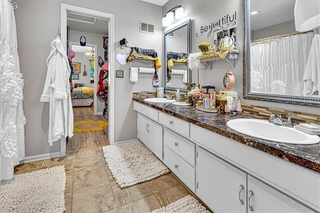 ensuite bathroom with double vanity, connected bathroom, visible vents, and a sink