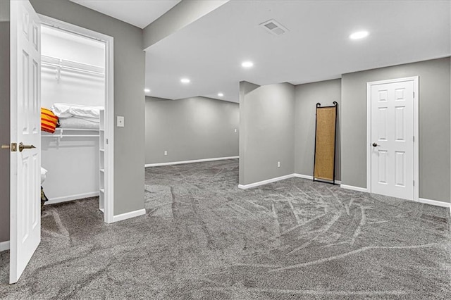 below grade area featuring baseboards, dark carpet, visible vents, and recessed lighting