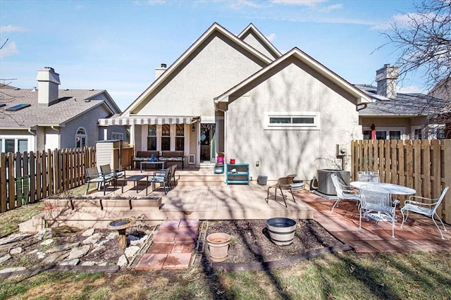 rear view of house featuring a patio, cooling unit, fence private yard, stucco siding, and outdoor dining space