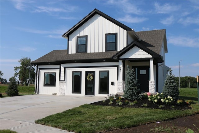 modern farmhouse featuring board and batten siding, a shingled roof, and a front lawn