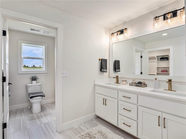 bathroom with double vanity, a sink, visible vents, and baseboards