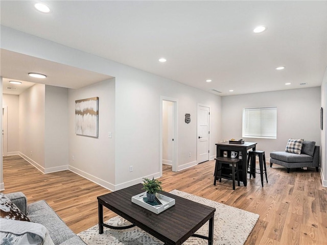 living room featuring baseboards, light wood-type flooring, and recessed lighting