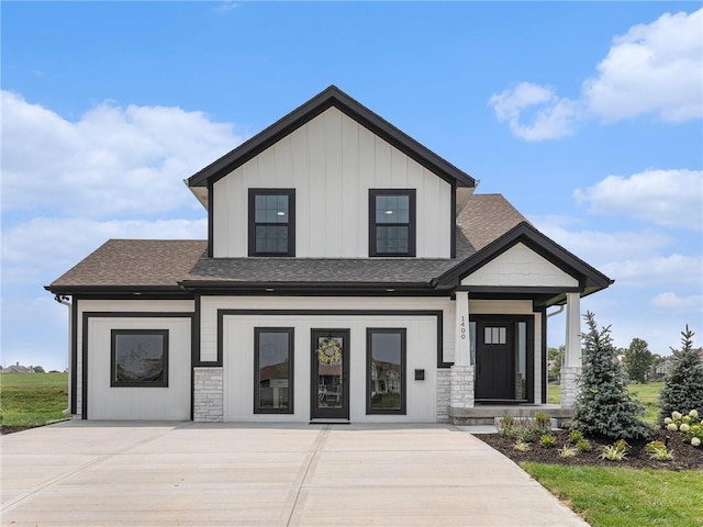 modern farmhouse style home with stone siding, roof with shingles, and board and batten siding