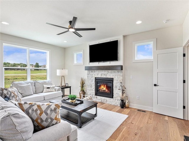 15619 Sheridan Ct, Basehor, KS 66007 - living room with a stone fireplace, a ceiling fan, light wood-style floors, healthy amount of natural light, and recessed lighting