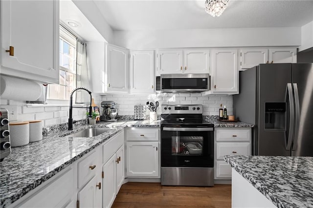 kitchen with dark wood-style floors, white cabinetry, stainless steel appliances, and a sink